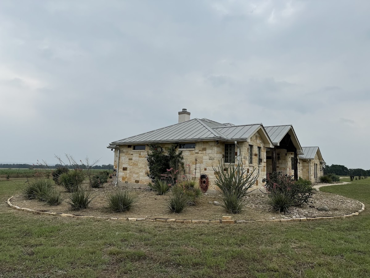 A Hill Country home with a circular landscaped flower bed at the entrance