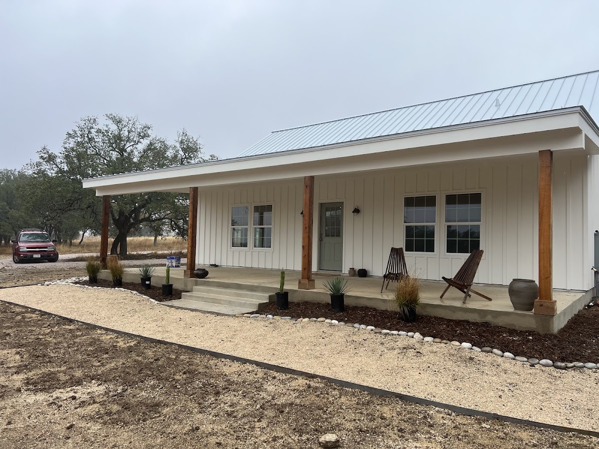 A white board-and-batten farmhouse with fresh front landscaping